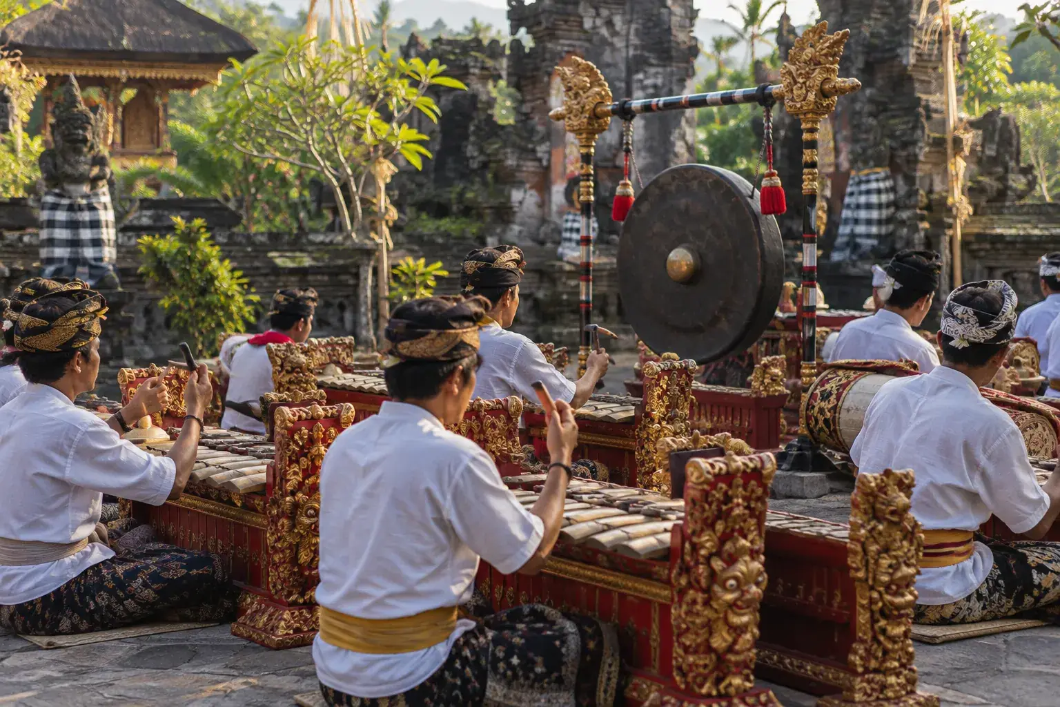 Des musiciens lèvent leurs maillets au-dessus des gangsa, devant un grand gong suspendu.