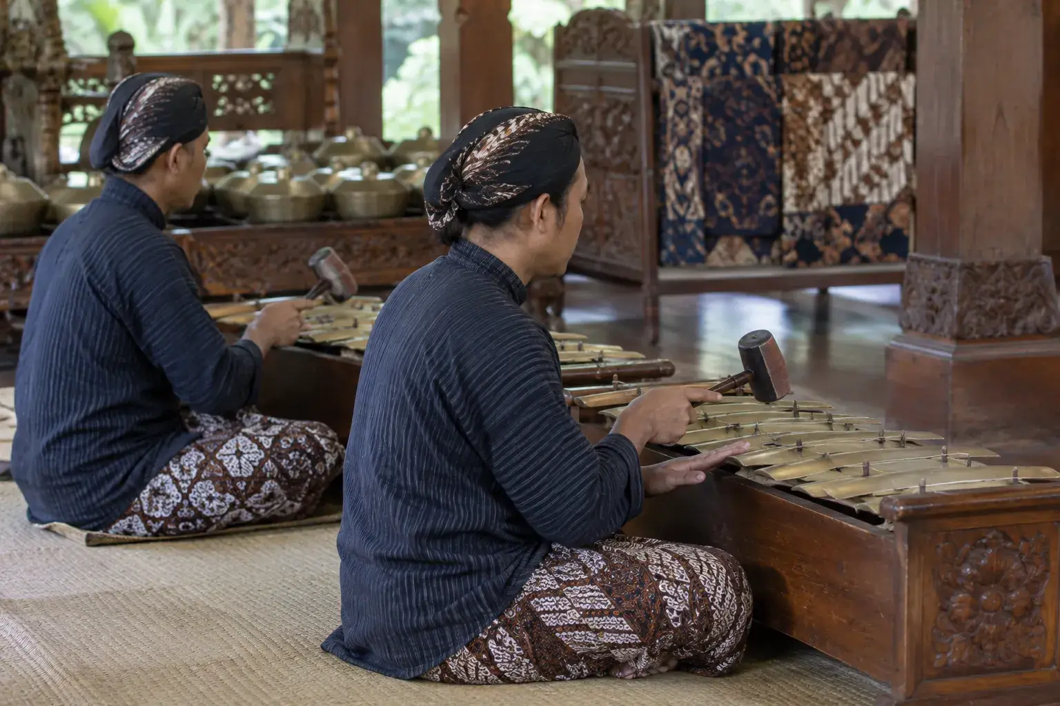 Deux musiciens javanais jouent des métallophones de gamelan, assis devant leurs claviers de bronze.
