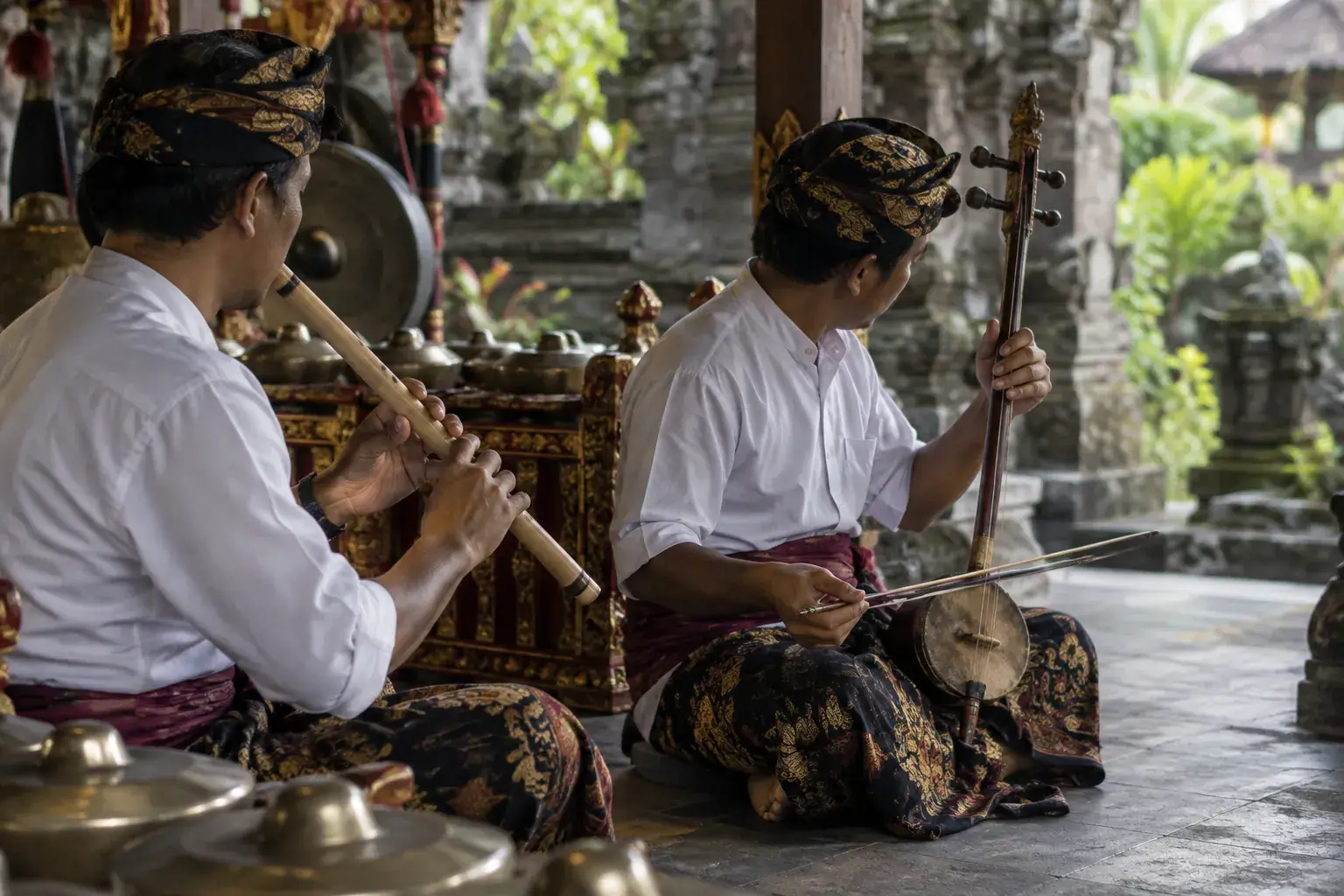 Un musicien souffle dans un suling en bambou tandis qu’un autre joue du rebab à deux cordes.
