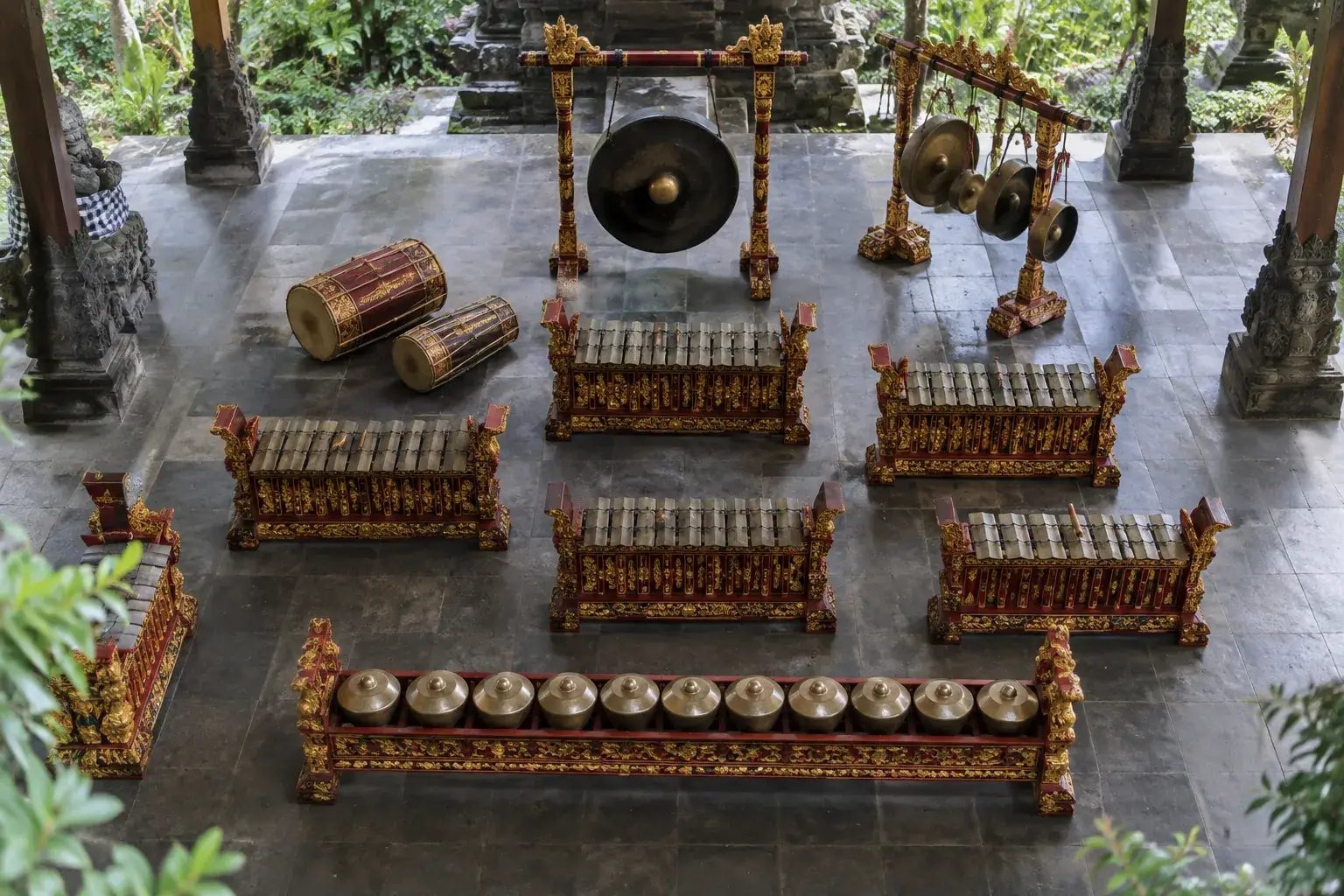 Vue en plongée d’un gamelan disposé sur un sol carrelé, avec métallophones, gongs et tambours.